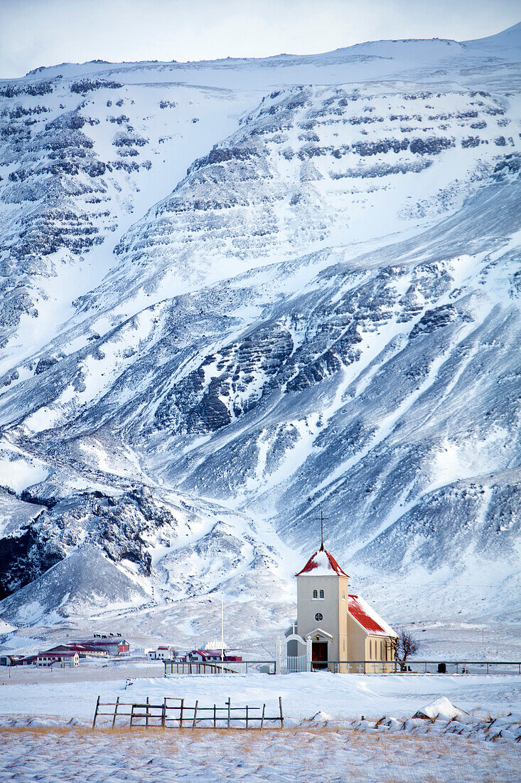 Kirche und abgelegener Bauernhof gegen Schnee bedeckten Berge, Winternachmittag auf der Straße zur Snaefellsnes-Halbinsel, Island, polare Regionen