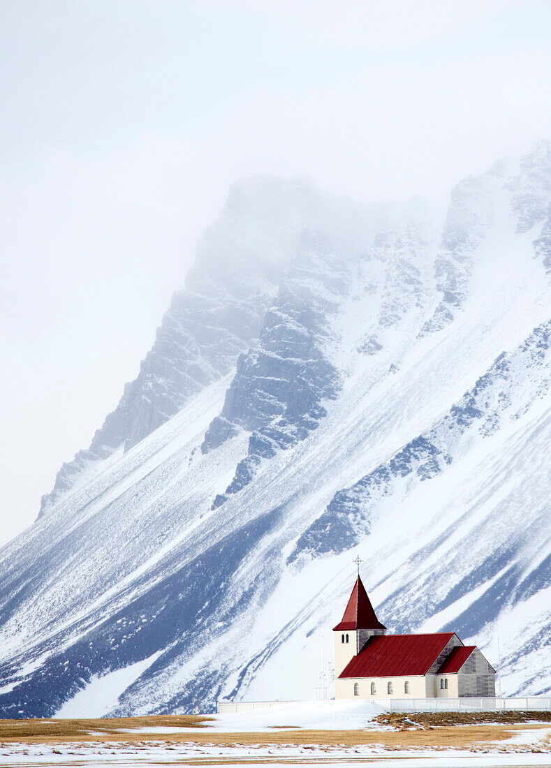 Kirche gegen Schnee bedeckte Berge, Winternachmittag, Halbinsel Snaefellsnes, Island, Polargebiete