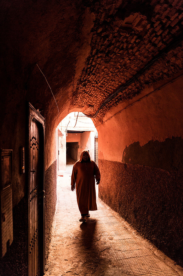 Lokaler Mann kleidete in traditionellem djellaba an, das durch Torbogen in einer Straße in der Kasbah, Marrakesch, Marokko, Nordafrika, Afrika geht