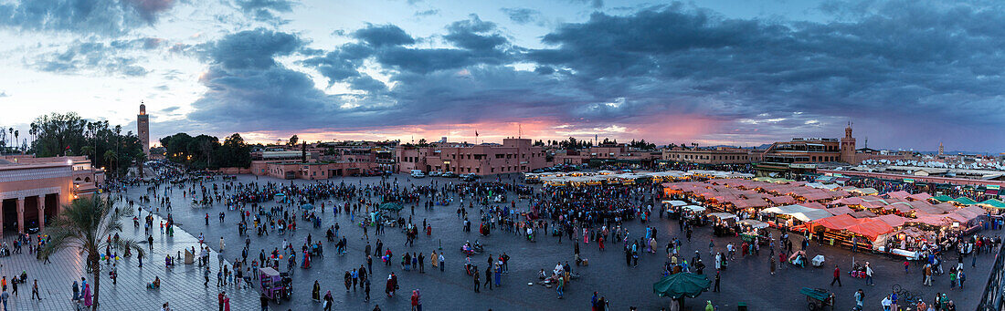 Panoramablick über den Djemaa el Fna bei Sonnenuntergang zeigt Koutoubia Minarett, Imbissstände, Geschäfte und Menschenmengen, Marrakesch, Marokko, Nordafrika, Afrika