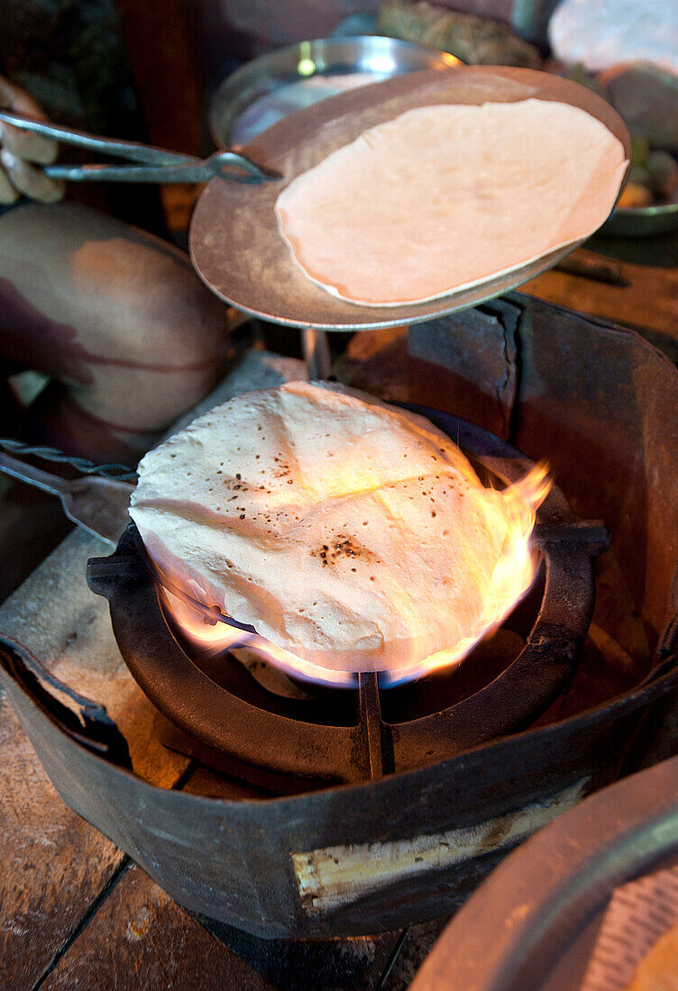 Street chapati maker, making bread over a naked flame using traditional basic equipment, Puri, Odisha, India, Asia