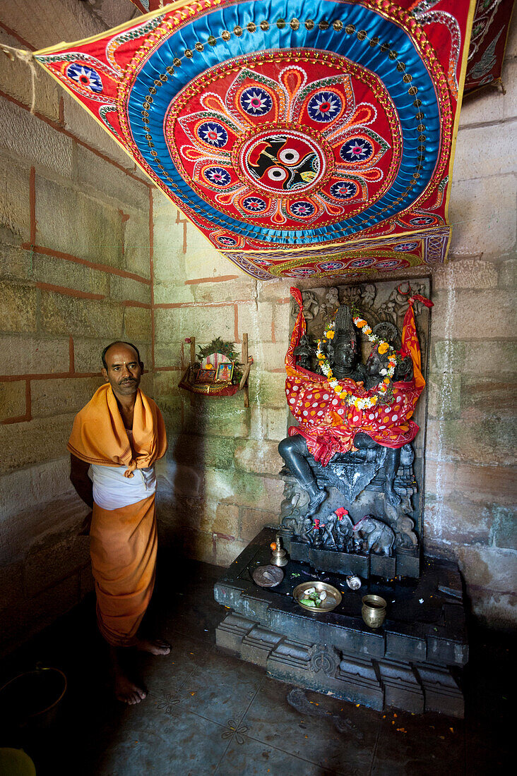 Hinduistischer Priester in Safran Roben am Radha Krishna Schrein in winzigen ländlichen Tempel, Chaurasi, Prachi Valley, Odisha, Indien, Asien