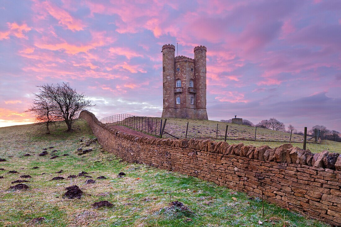 Broadway Tower and Cotswold drystone wall at sunrise, Broadway, Cotswolds, Worcestershire, England, United Kingdom, Europe