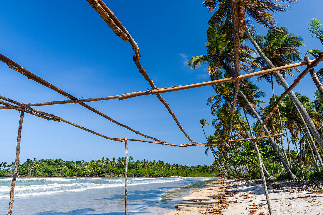 Photograph of wooden frame on tropical beach with palm trees in background, Boipeba Island, Bahia, Brazil