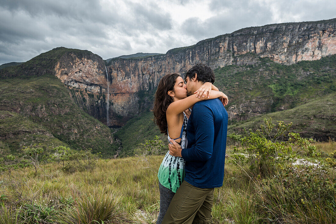 Side view of couple embracing and kissing against Tabuleiro Waterfall in Serra do Intendente State Park, Minas Gerais, Brazil