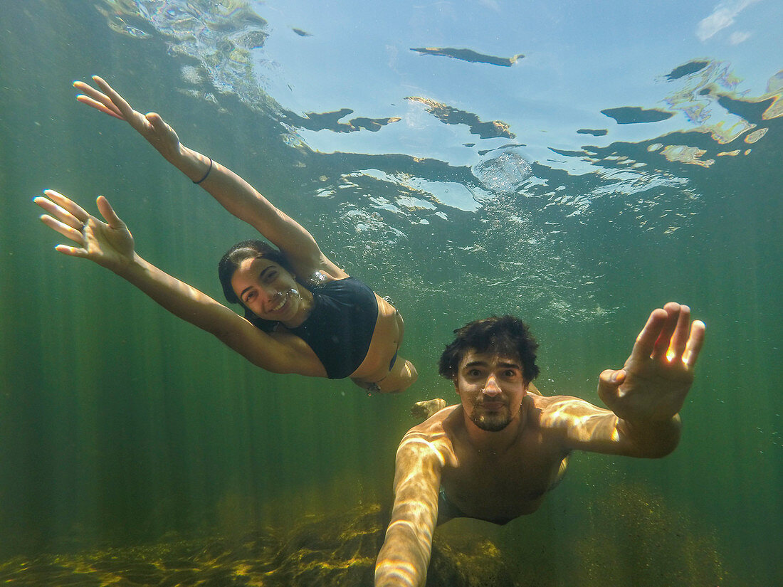 Underwater selfie of smiling swimming couple, Serra do Cipo National Park, Minas Gerais, Brazil