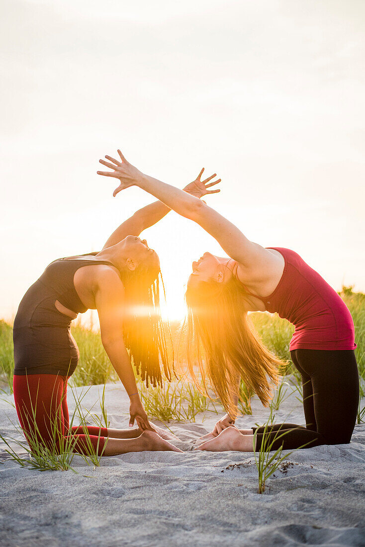 Fotografie von zwei Frauen, die zusammen Yoga in der Kamel-Haltung (Ustrasana Veränderung), Newport, Rhode Island, USA tun.