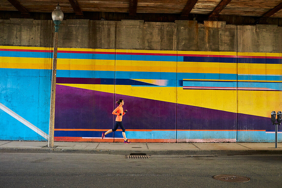 Woman running past underpass mural in Boston, Massachusetts, USA