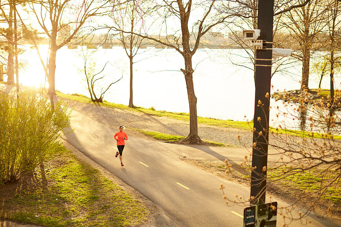 Female jogger running in park beside Charles River, Boston, Massachusetts, USA