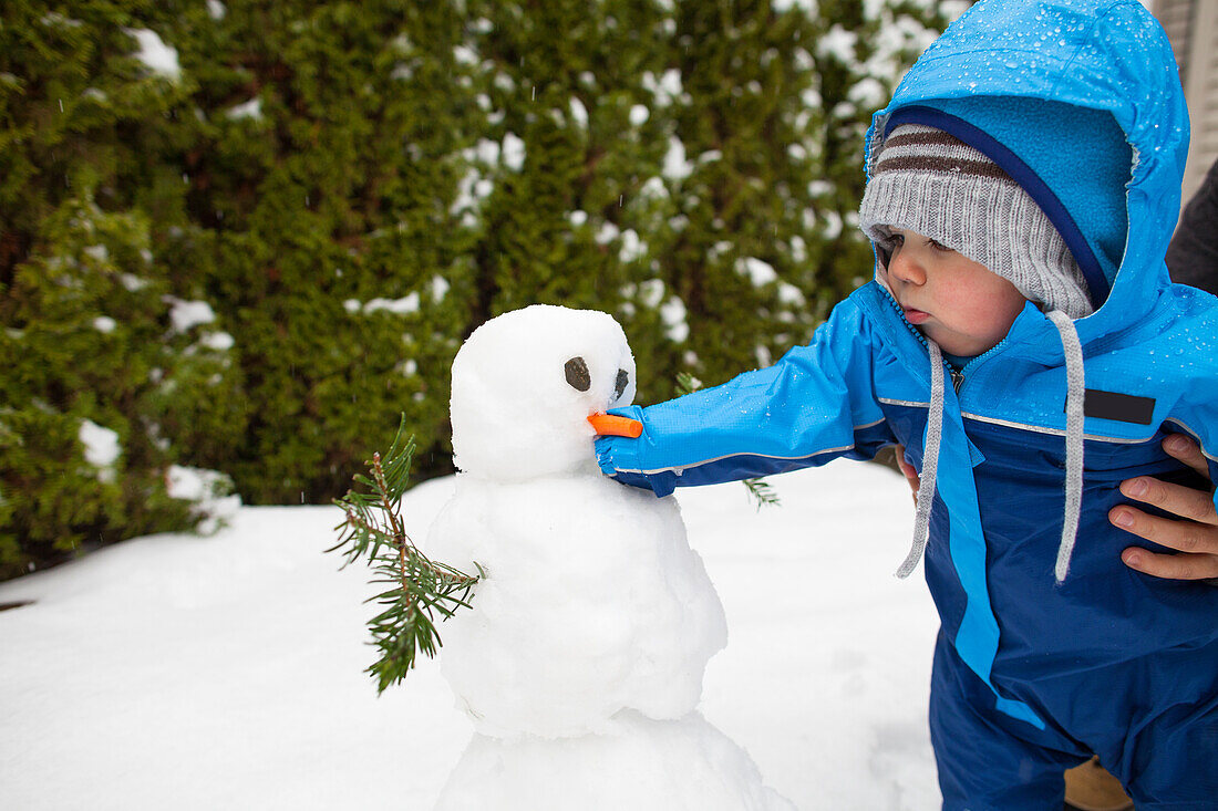 Winter scene with baby boy building snowman, Langley, British Columbia, Canada
