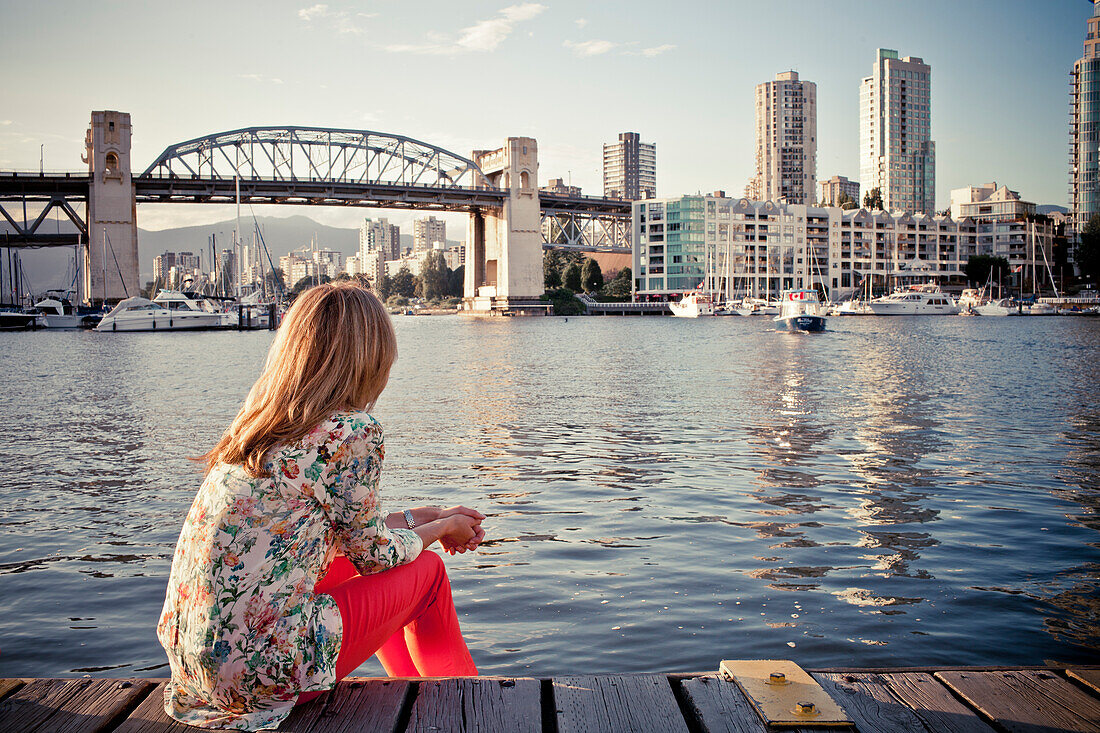 Photograph of single woman sitting on waterfront of False Creek, Vancouver, British Columbia, Canada
