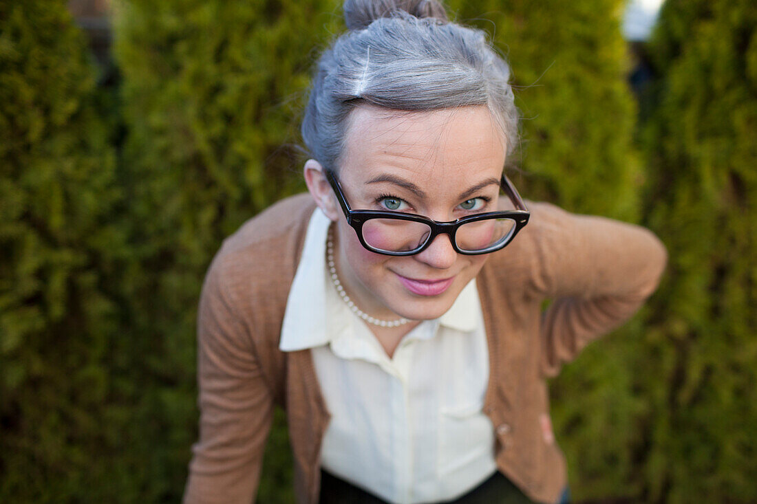 Photograph of young woman dressed as old woman with gray hair and eyeglasses, Vancouver, British Columbia, Canada