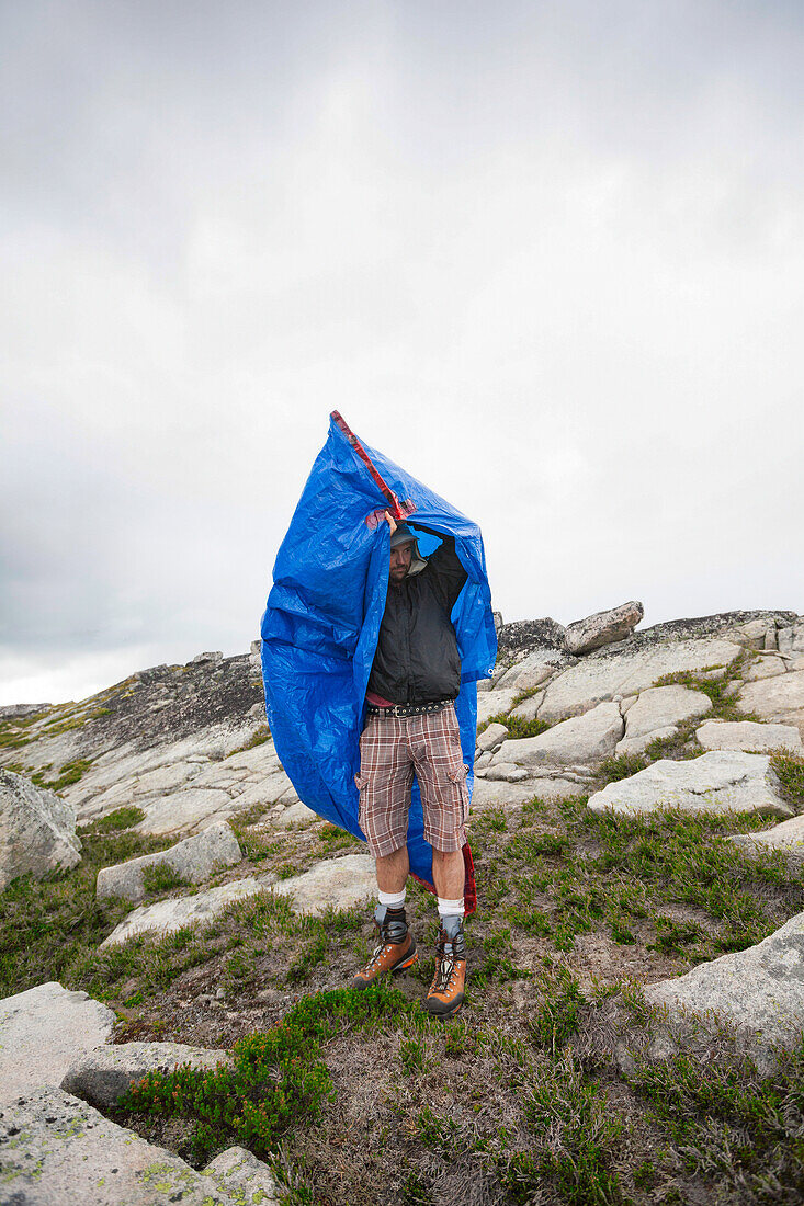 Photograph of mountaineer taking shelter in tarp bag, Chilliwack, British Columbia, Canada