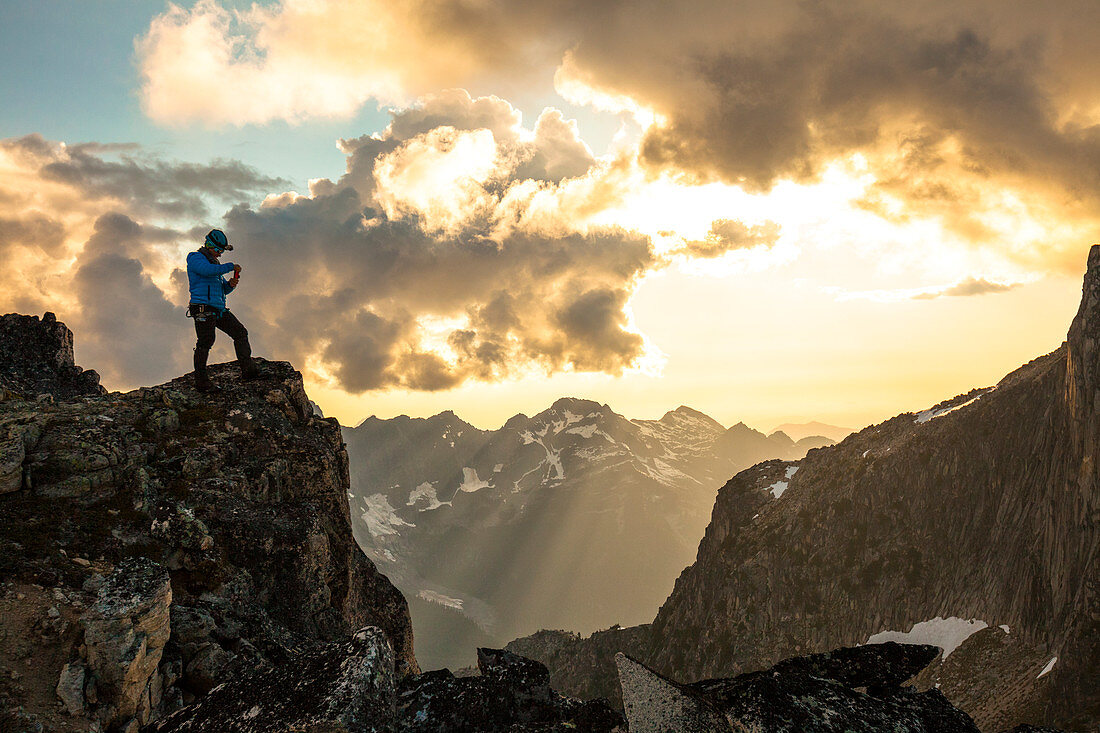 Majestic photograph with mountain climber photographing view at sunset in North Cascade Mountain Range, Chilliwack, British Columbia, Canada