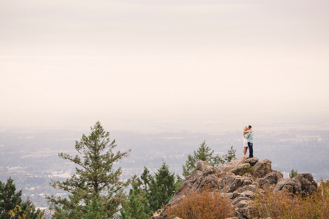 Seitenansicht von den jungen Paaren, die oben auf Hügel während der Tageszeit, Eugene, Oregon, USA umarmen.