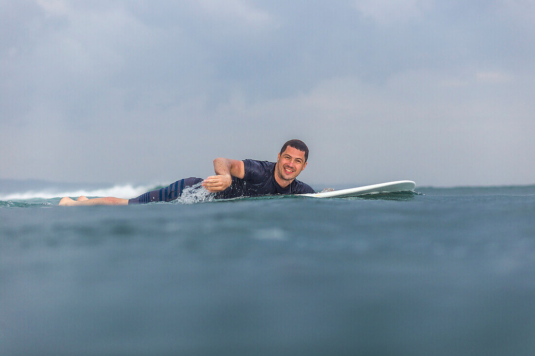 Surfer, der auf dem Meer schaufelt