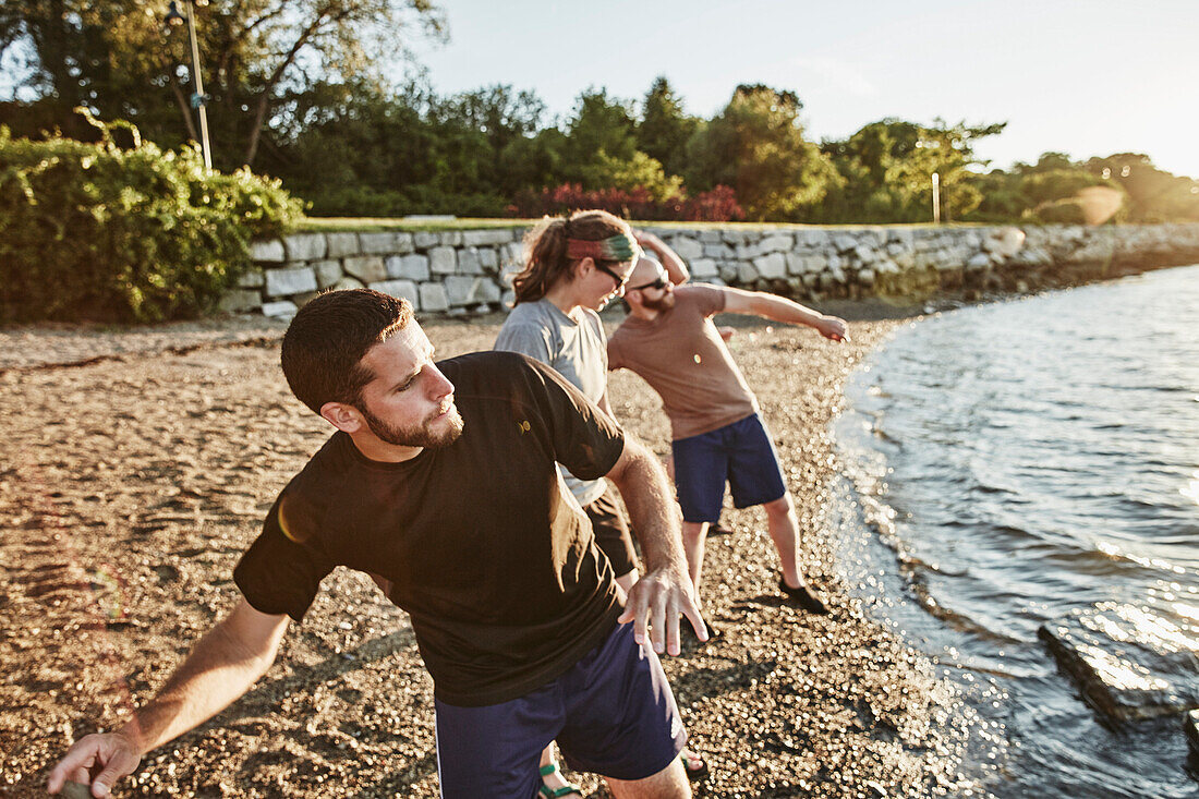 Photograph of three friends skipping rocks on beach, Casco Bay, Portland, Maine, USA
