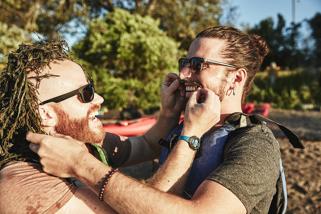 Photograph of two friends having fun with seaweed, Portland, Maine, USA