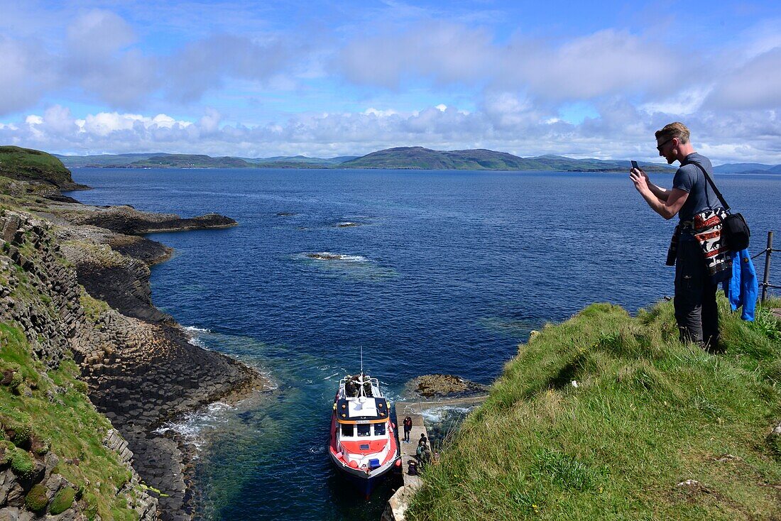 Mann fotografiert Ausflugsboot, Vulkaninsel Staffa, Südteil der Insel Mull, Schottland
