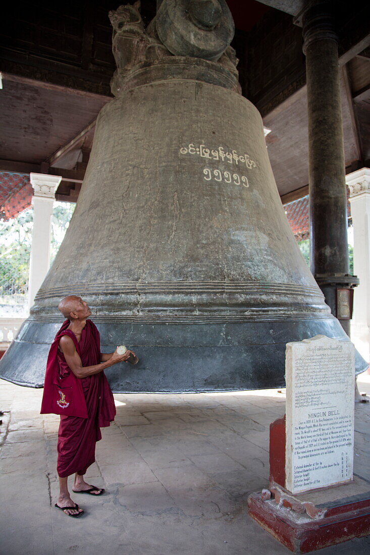 Buddhist monk rings giant Mingun Bell (the heaviest functioning bell in the world), Mingun, Sagaing, Myanmar