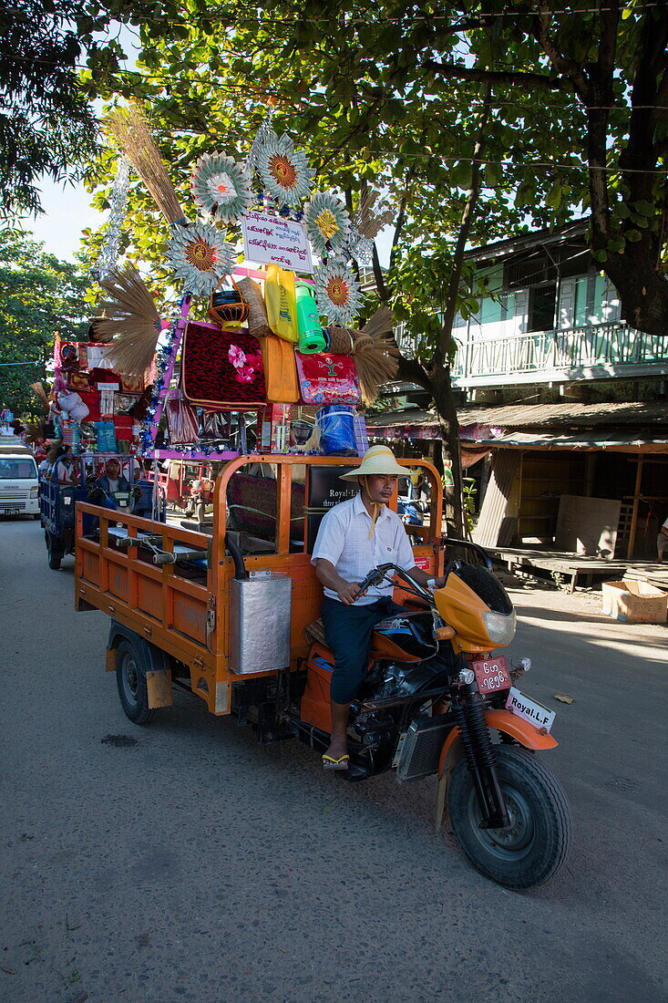 Tuk-tuk auto rickshaw during procession carrying food and gifts to monastery, Bhamo, Kachin, Myanmar