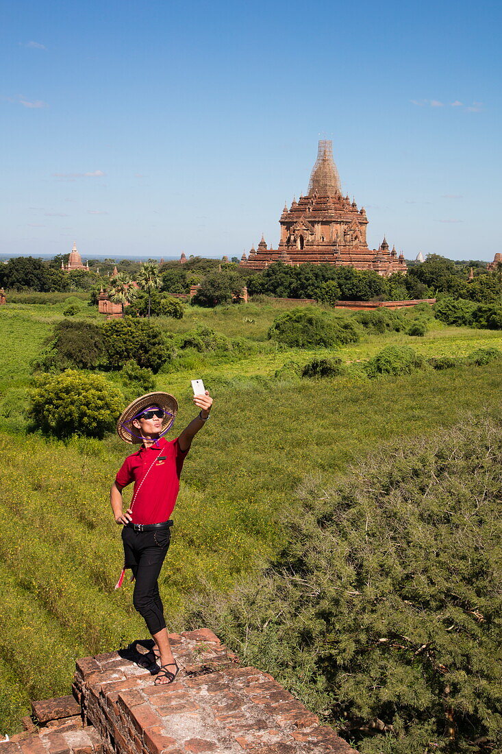 Man takes selfie snapshot amidst ancient temples of Bagan, Bagan, Mandalay, Myanmar