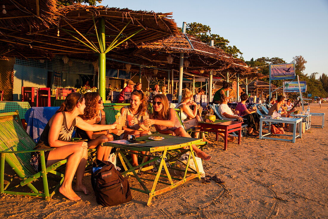 Four young women enjoy cocktails at The Green Umbrella beach restaurant and bar at Ngapali Beach, Ngapali, Thandwe, Myanmar