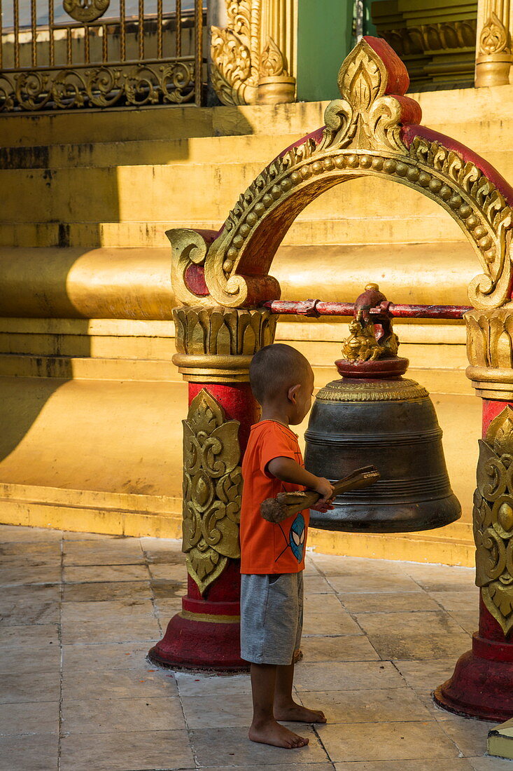 Young boy rings bell at Sule Pagoda, Yangon, Yangon, Myanmar