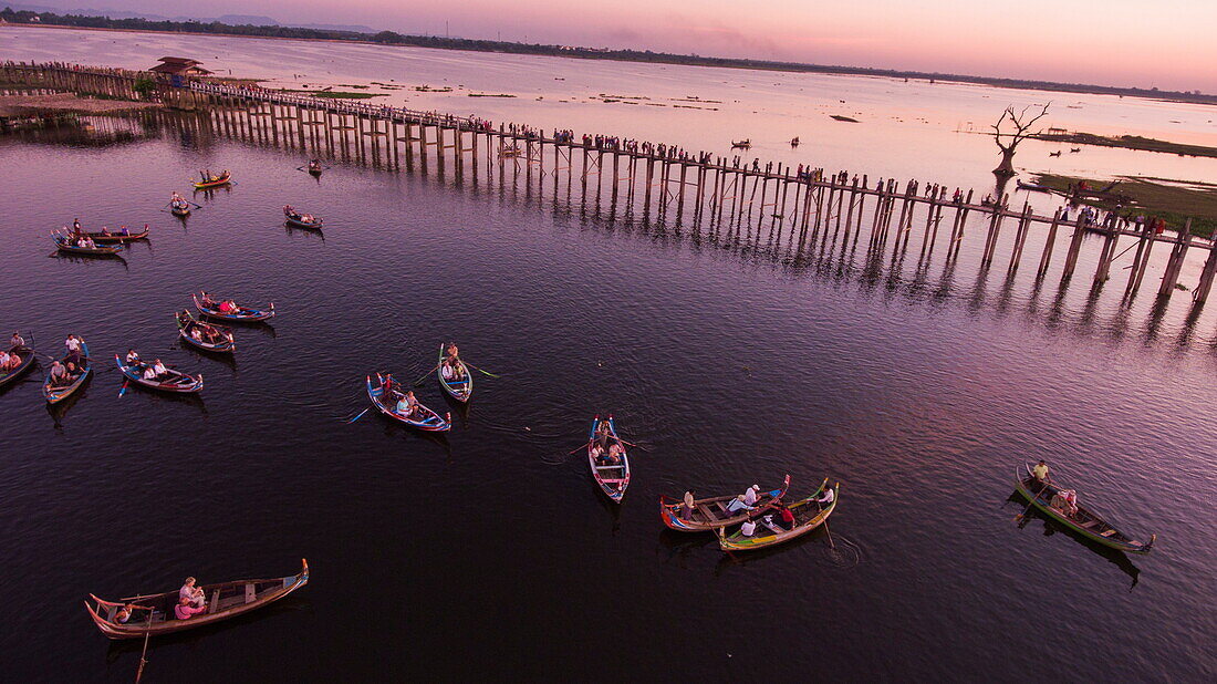 Aerial of tourists on U Bein Bridge and rowboats on Taungthaman Lake at sunset, Amarapura, Mandalay, Myanmar