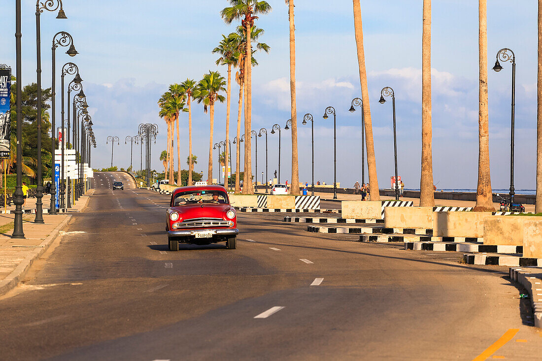 Classic cars ride along the Malecon Seawall in the harbor of Havana, Cuba