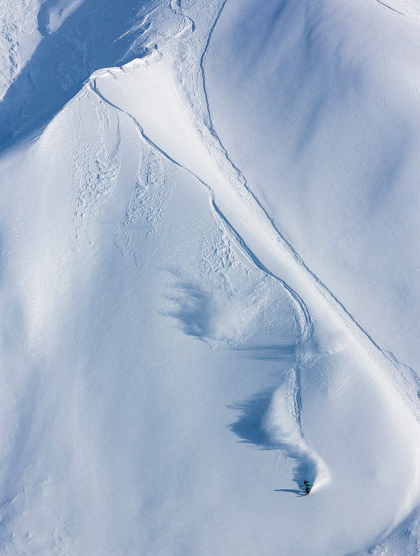 Professioneller Snowboarder und olympischer Goldmedaillengewinner 2014, Jamie Anderson, reitet frisches Pulver an einem sonnigen Tag beim Snowboarding in Haines, Alaska.