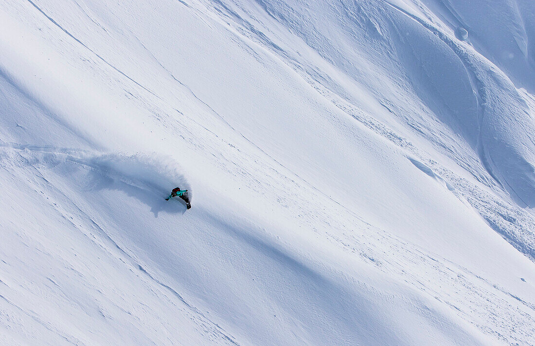 Professioneller Snowboarder und olympischer Goldmedaillengewinner 2014, Jamie Anderson, reitet frisches Pulver an einem sonnigen Tag beim Snowboarding in Haines, Alaska.