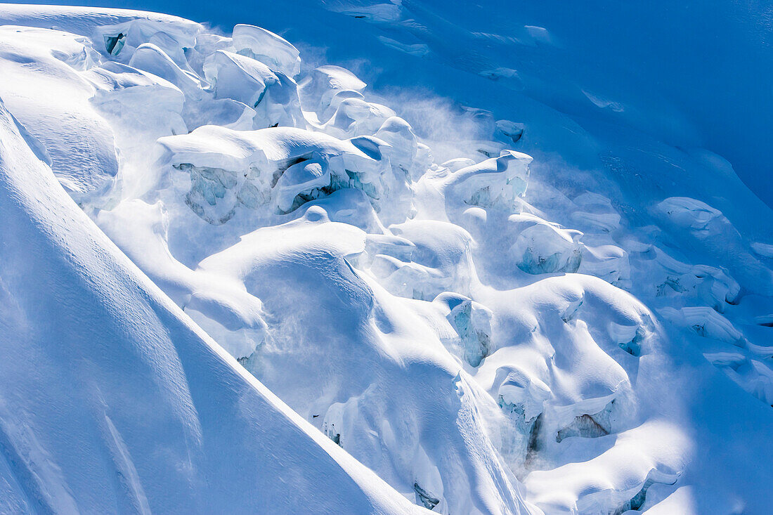 A glacier with crevasses is covered with a fresh layer of snow on a sunny day in Haines, Alaska