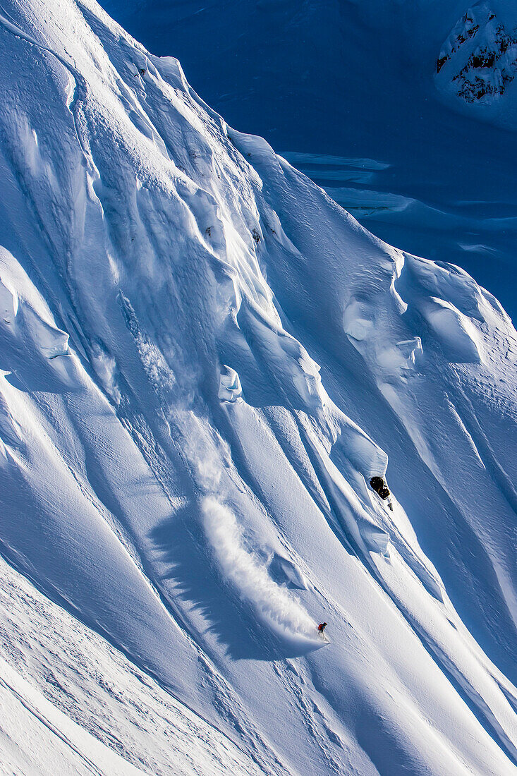 Professional snowboarder Robin Van Gyn, rides fresh powder on a sunny day while snowboarding in Haines, Alaska.