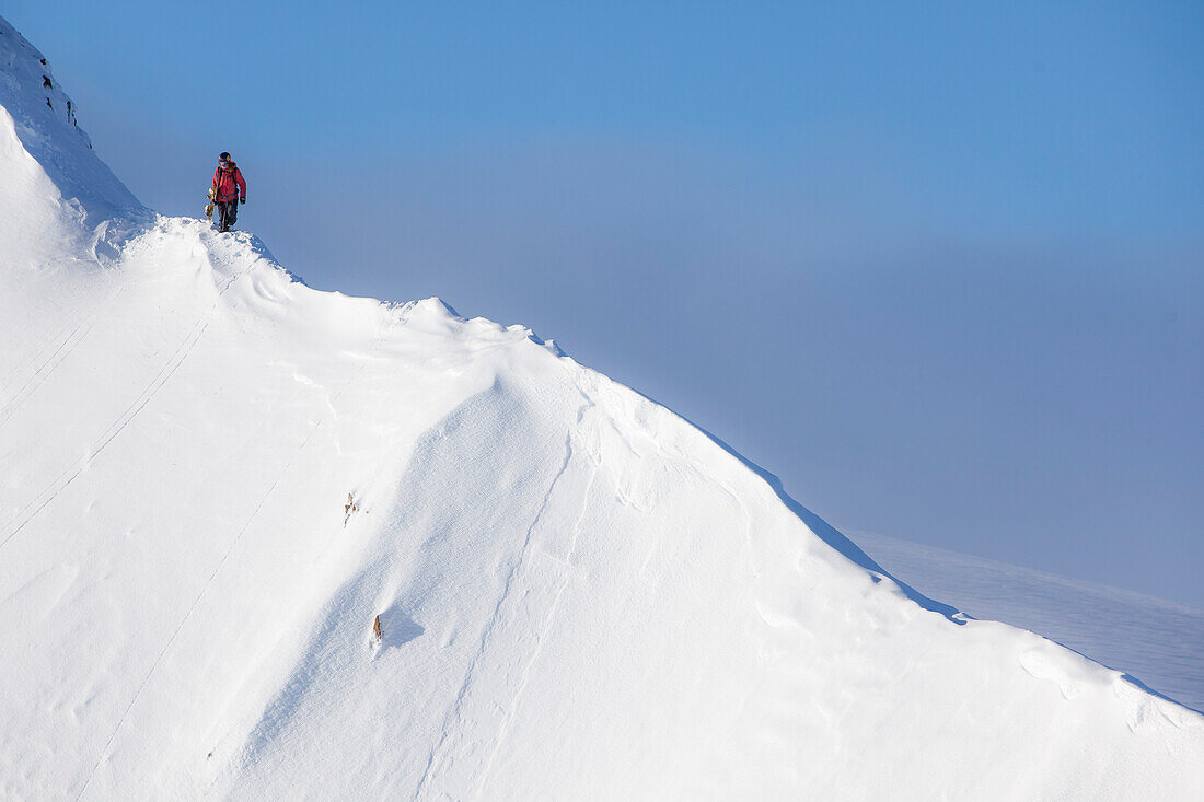 Profi-Snowboarder Marie France Roy, geht entlang einer Kammlinie, um zu ihrer Linie an einem sonnigen Tag in Haines, Alaska zu kommen.