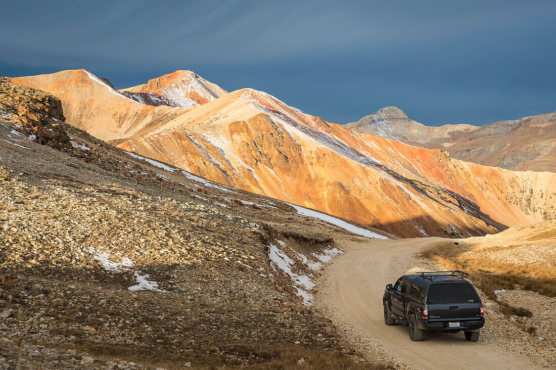 A truck driving on corkscrew passes in southern Colorado with storm clouds in the distance.