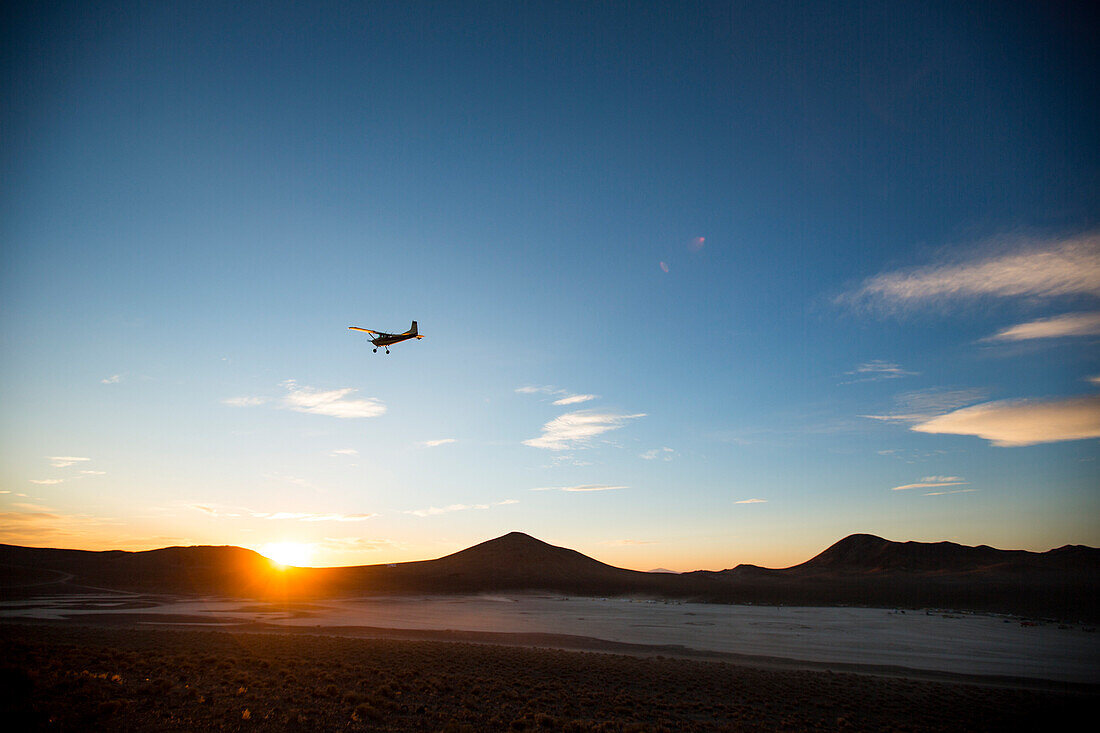 Airplane flies against sky at sunset over Nevada Desert