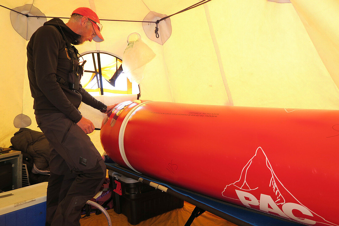 Ein Mountain Ranger und Sanitäter pumpt Luft in eine tragbare Höhenkammer im Medical Camp auf Denali