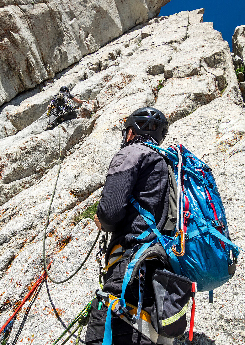 Mann, der seinen Freund betrachtet, der den Felsen klettert, der in den Wasatch-Bergen, Utah gelegen ist