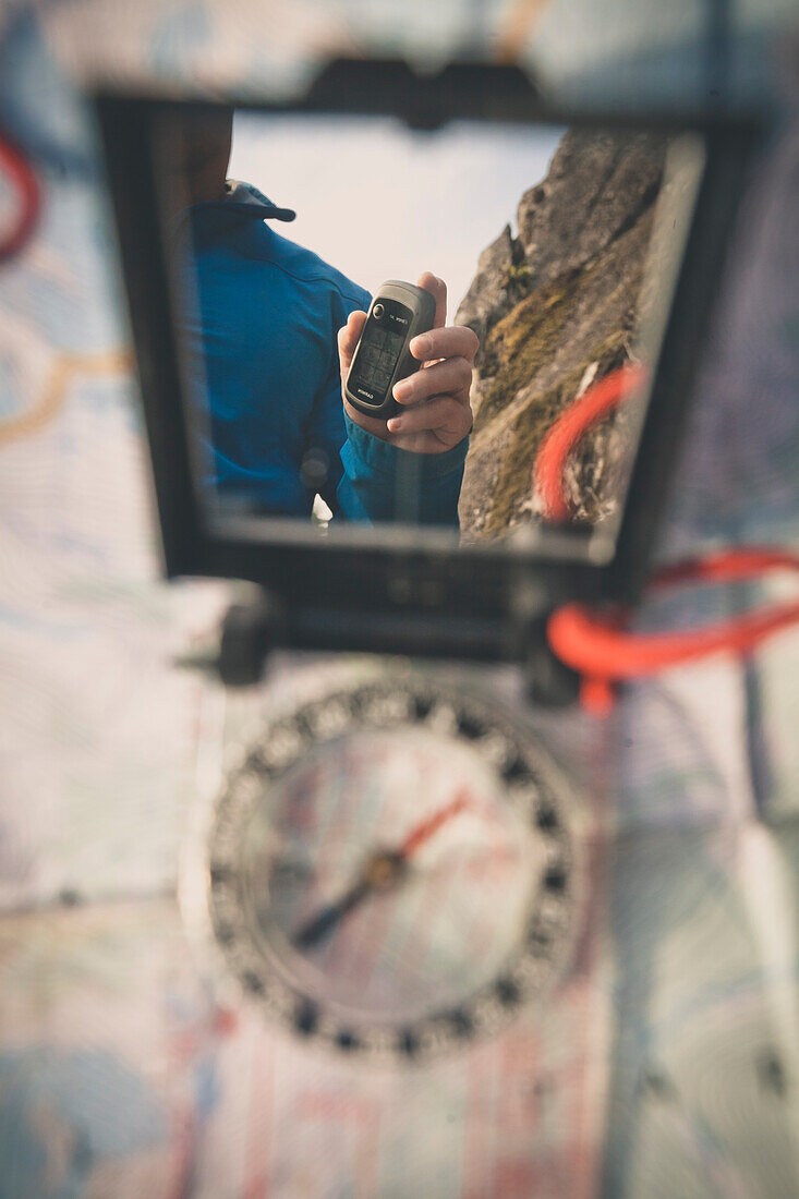 The person holding GPS reflected in the mirror of the navigation compass