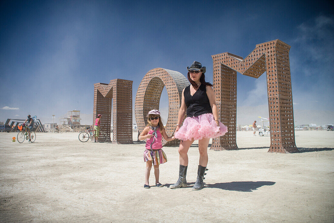 Mother and daughter in front of MOM art at Burning Man
