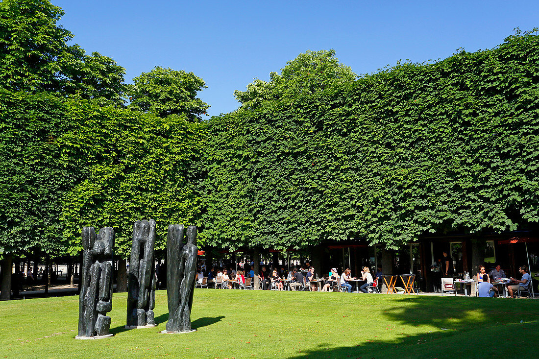 'Frankreich, Paris. 1. Arrondissement. Jardin des Tuileries. Skulptur ''Charaktere III'' von Stephen Martin. Touristen außerhalb eines Restaurants im Hintergrund.'