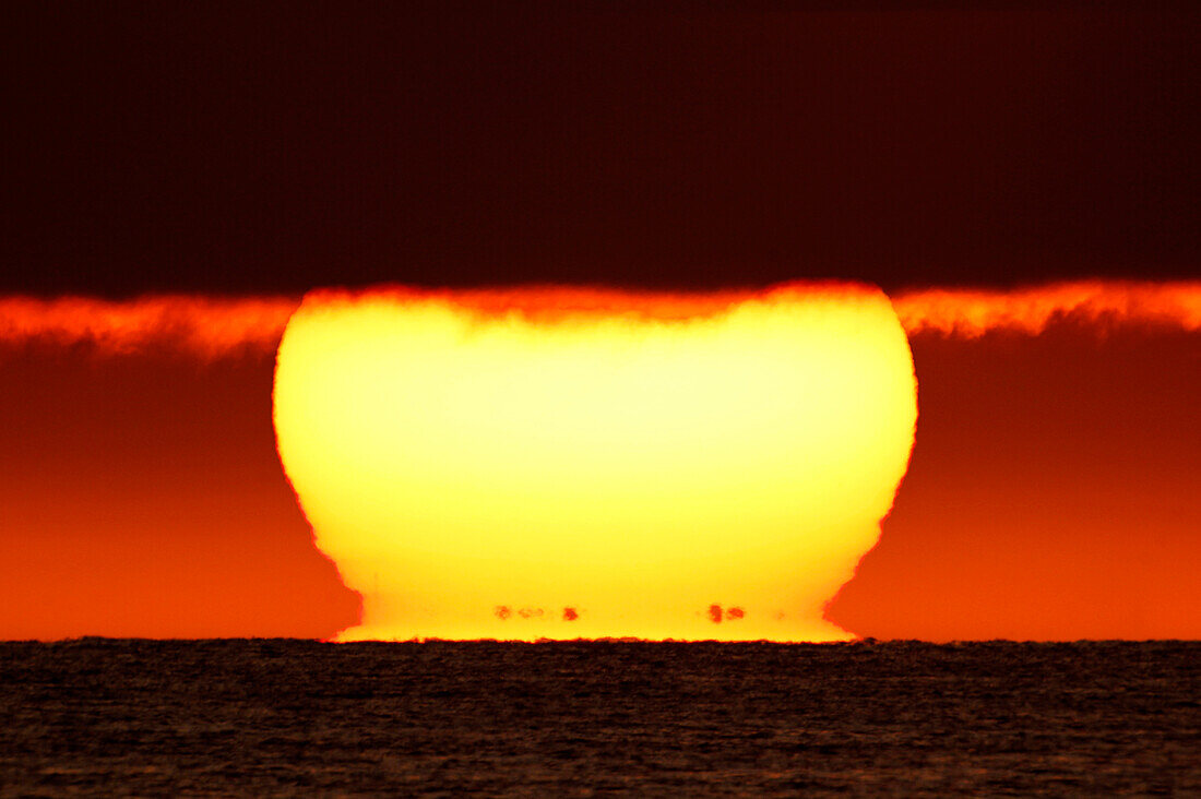 Frankreich, Normandie, Montmartin-sur-Mer, Sonnenuntergang. Die schwarzen Punkte am Fuß der Sonne sind die Küsten von Jersey