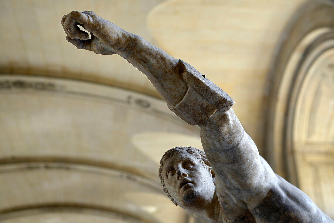 France, Paris, detail of a marble statue of an ancient soldier arm raised at the Louvre Museum