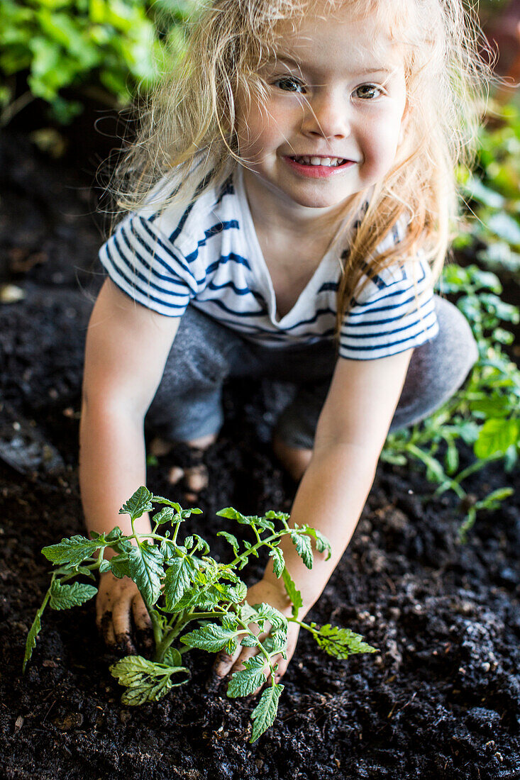 Caucasian girl posing with plant in garden
