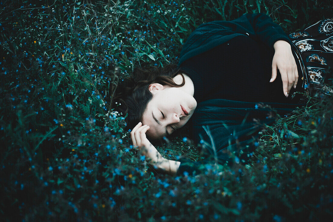 Caucasian woman laying in field of wildflowers