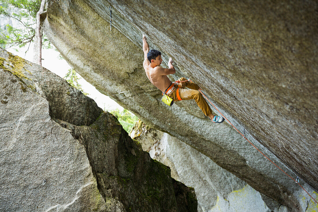 Mixed race boy rock climbing