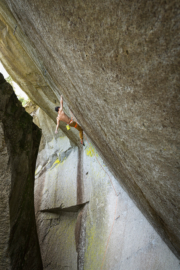 Mixed race boy hanging from rock