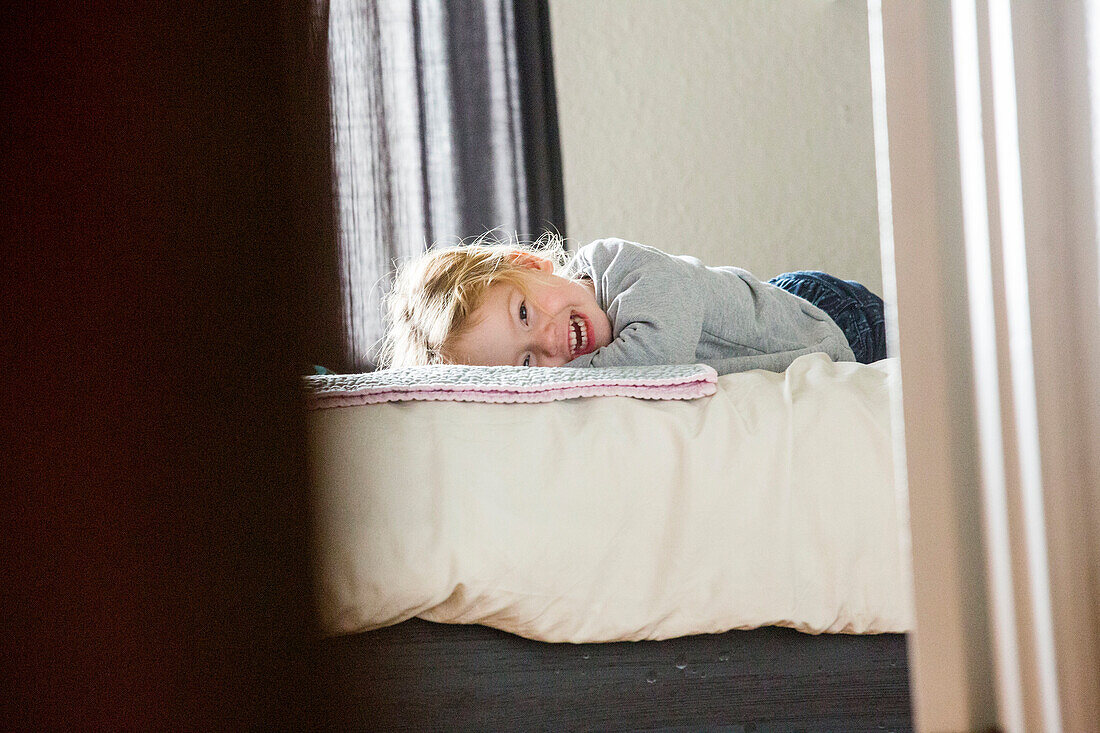 Caucasian girl laying on bed beyond doorway
