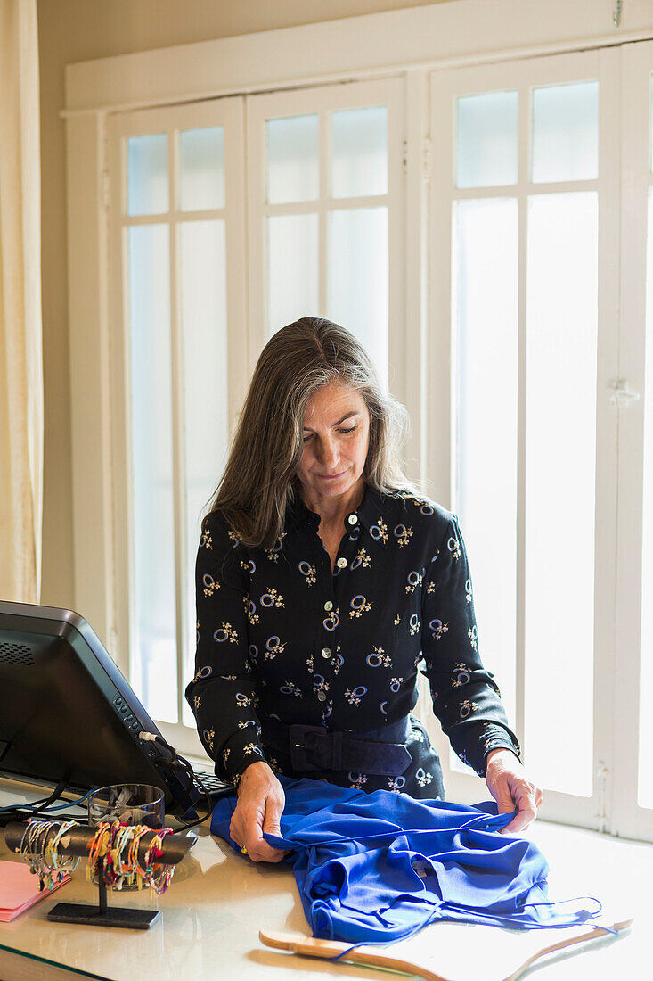 Caucasian woman holding clothing near computer